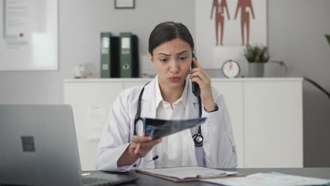 stressed indian female doctor explaining x ray report to patient on call