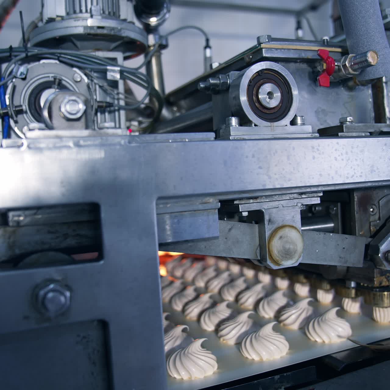Automatic machine for producing marshmallows. Complicated mechanism laying creamy desserts on the conveyor belt at food factory