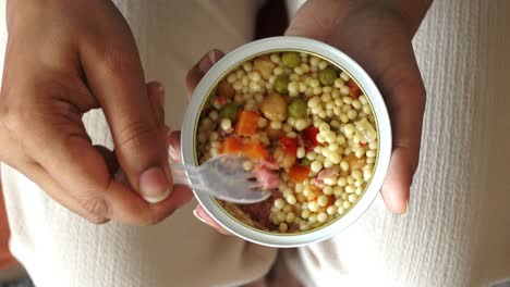 mujer comiendo una ensalada de pasta enlatada