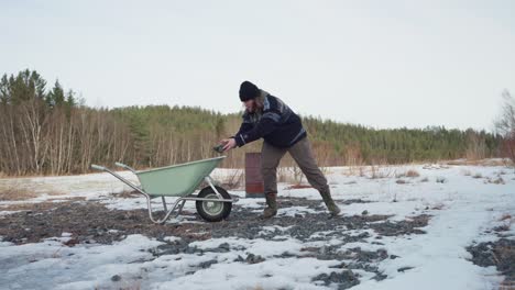 the man is loading the wheelbarrow with rocks for the diy hot tub project - static shot