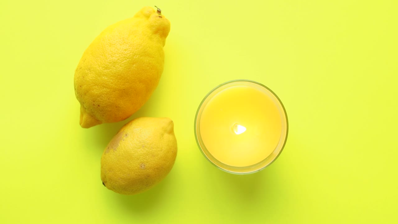 Lemons and Candle on Yellow Background