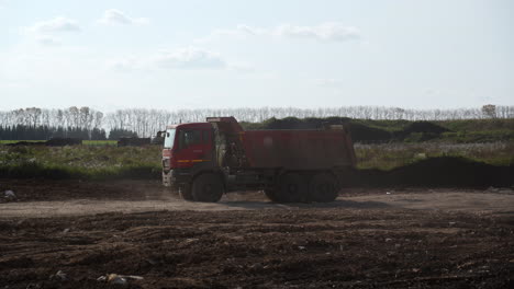 a red dump truck on a dirt road at a construction site