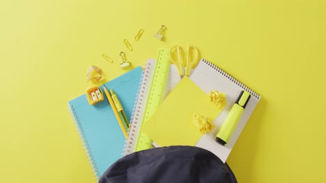 Video-of-blue-and-yellow-school-accessories-in-black-case-on-yellow-surface