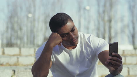 Serious-African-American-sportsman-looking-at-smartphone.