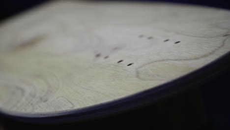 Close-up-slider-shot-of-skate-deck-sanded-and-prepared-to-be-coated-with-paint