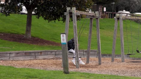 individual sitting on swing, using a phone