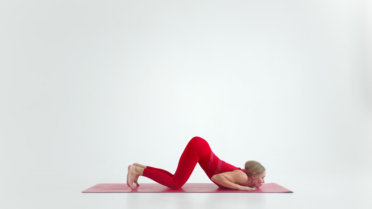 Schöne junge Frau in roter Sportkleidung macht Yoga- oder Pilates-Übungspose auf weißem Hintergrund.
