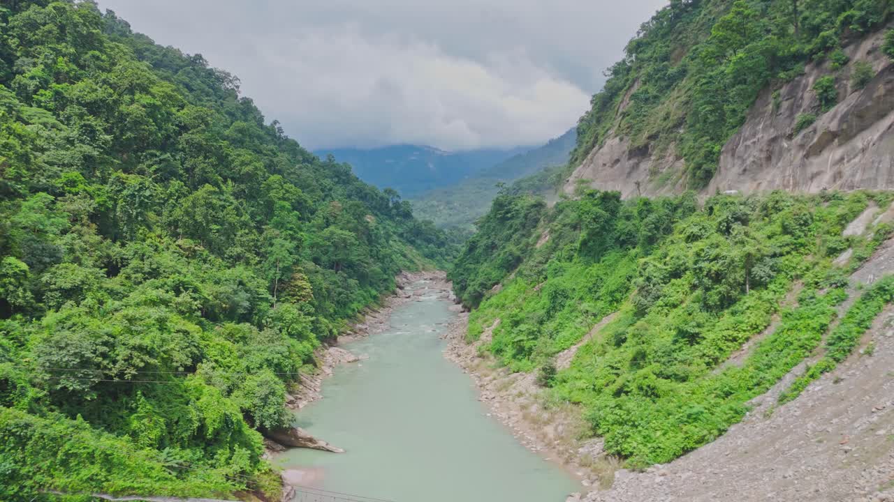 Aerial drone footage of rivers flowing between lush green mountains, showcasing the untouched beauty of Nepal’s natural landscape and stunning valley terrain surrounded by vibrant hills