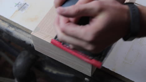 finish sanding the wood filler on wooden floating shelves in preparation to be stained and hung in a remodeled bathroom