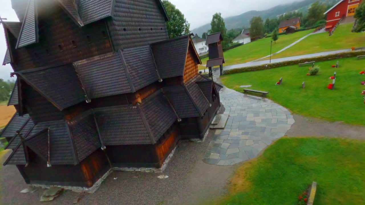 Old wooden church in Norway, aerial view with surrounding green field and cemetery