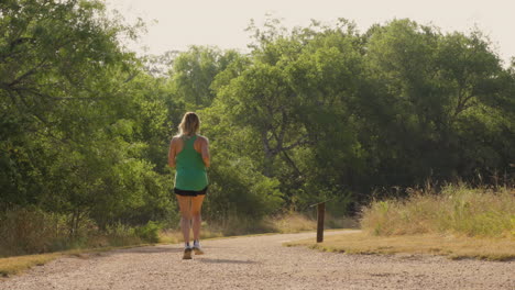 a slow-motion shot captures a woman running gracefully on a scenic trail, highlighting her movement and the beauty of the surrounding nature as she embraces the outdoors.