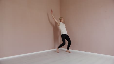 man in white shirt and black pants dances in a studio