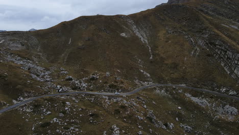 drone shot of car driving through the mountains with rocks in montenegro