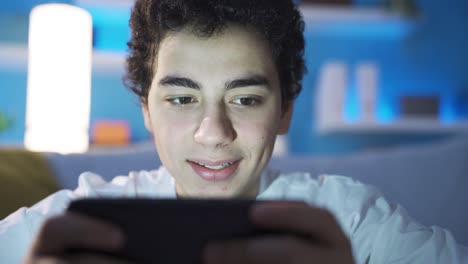 adolescent male watching videos on smartphone alone at home. videos with useful and interesting content. movies.