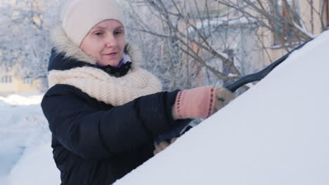 una mujer quita la nieve de su coche