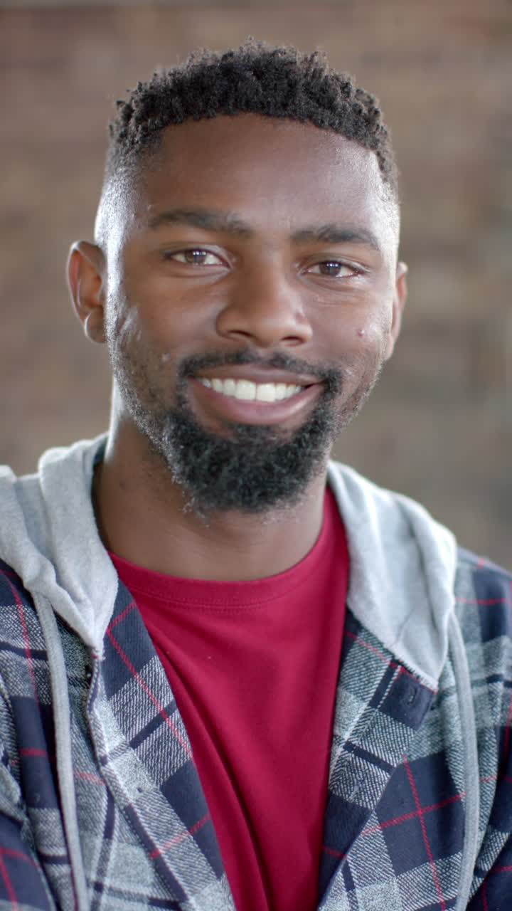 Vertical video of portrait of happy african american casual businessman in office in slow motion