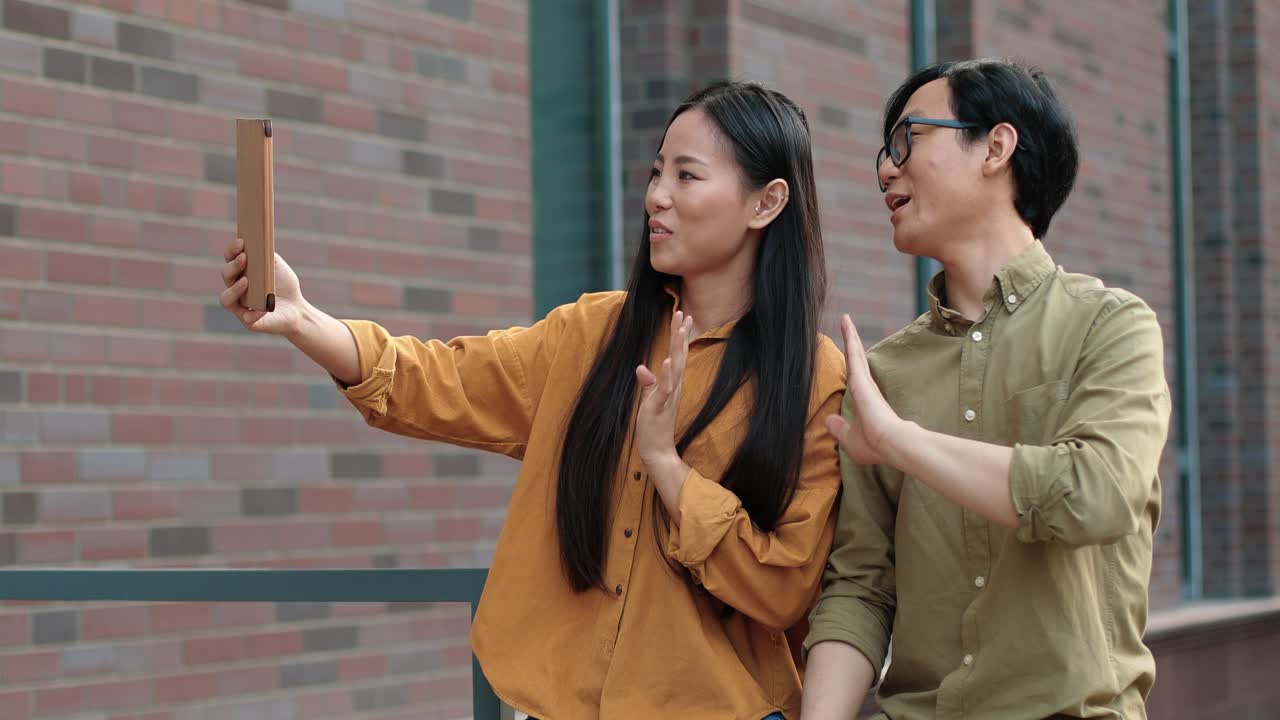 대학 근처 거리에서 태블릿으로 화상 통화를 하는 아시아 학생들