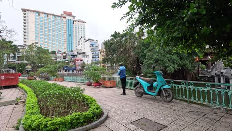 man stands by motorbike in city park