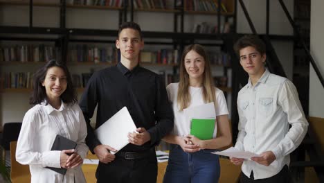 zoom in portrait of four multi ethnic young people standing together in group looking at camera posing at library or in modern