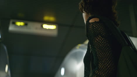 close up rear view shot of woman riding up escalator on london underground train station shot in real time