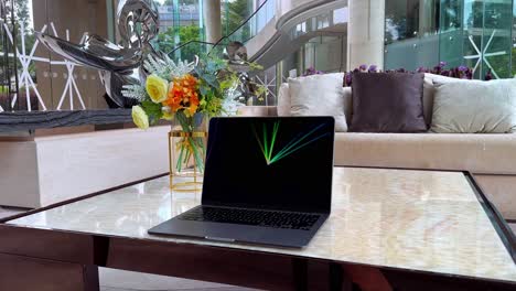 macbook laptop displaying screensaver on a table inside a luxurious upscale home