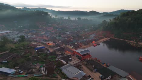 aerial dolly establishing of ban rak thai, northern thailand, lush lmisty andscapes and scenic lake surrounded by homes