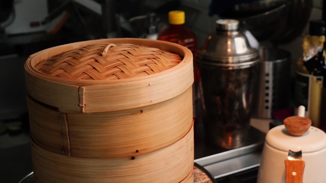 Close up shot of a Japanese steamer. The Steamer is placed over hot water and steam cooks the contents of the bamboo cases in the rustic kitchen.
