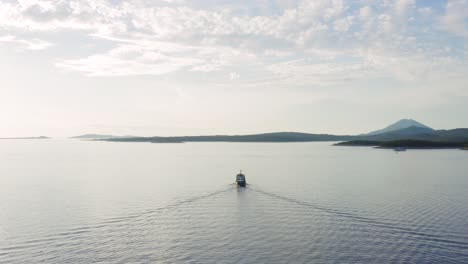 Aerial-shot-of-a-boat-slowly-sailing-away-towards-fog-covered-islands-near-Losinj,-Croatia