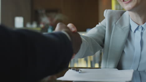 businesswoman signing contract and giving handshake