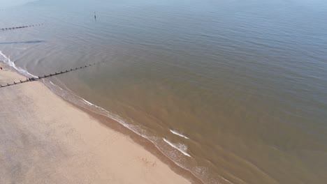 Sunny-aerial-view-over-golden-sandy-beach-idyllic-ocean-tide-seascape