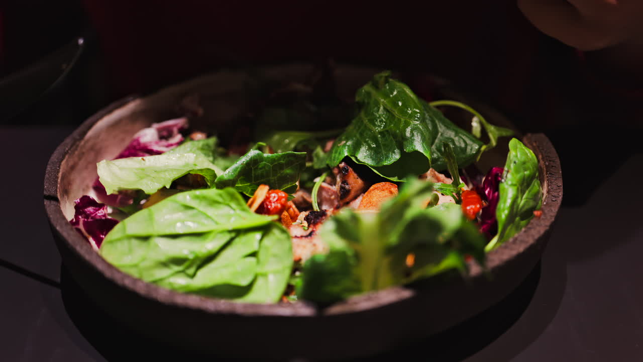 Close up of a woman cutting and eating a salad at a restaurant
