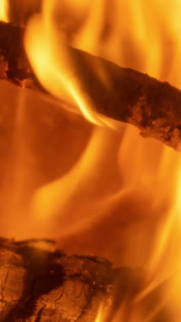 a close up of flames in log fire burning in a fireplace in vertical