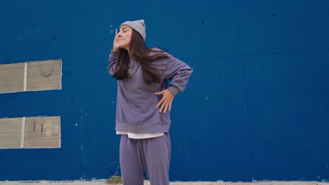 woman in street style dancing against a blue wall