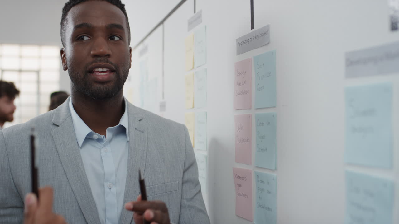 corporate business people meeting using sticky notes brainstorming caucasian team leader man sharing problem solving strategy on whiteboard working on solution for project deadline