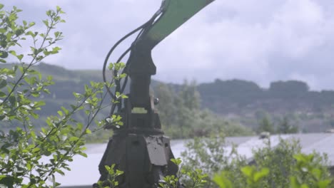 Giant Industrial Excavator Grab Machine Rising and Dipping After Picking Up Scrap Metal and Waste Junk Material with Warehouses in Background at Junkyard. Used for Disposing of Rubbish and Recycling.