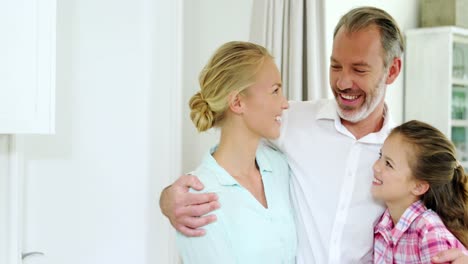 Smiling-family-standing-with-arm-around-at-home