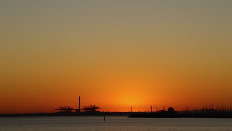 sunset view over melbourne harbor with cranes