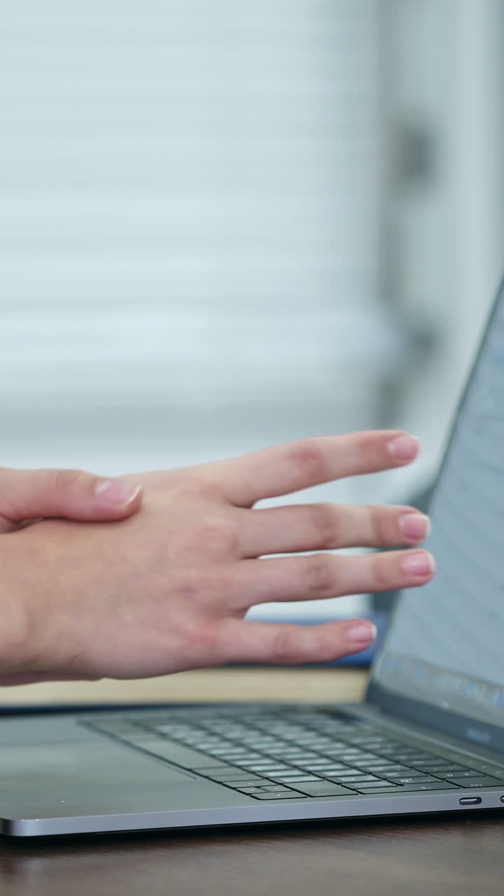Woman using laptop indoor. Close up of woman working at home office, hand on keyboard. Vertical video