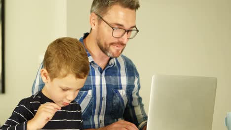 Padre-E-Hijo-Usando-Laptop-Y-Tableta-Digital-En-La-Sala-De-Estar-4k