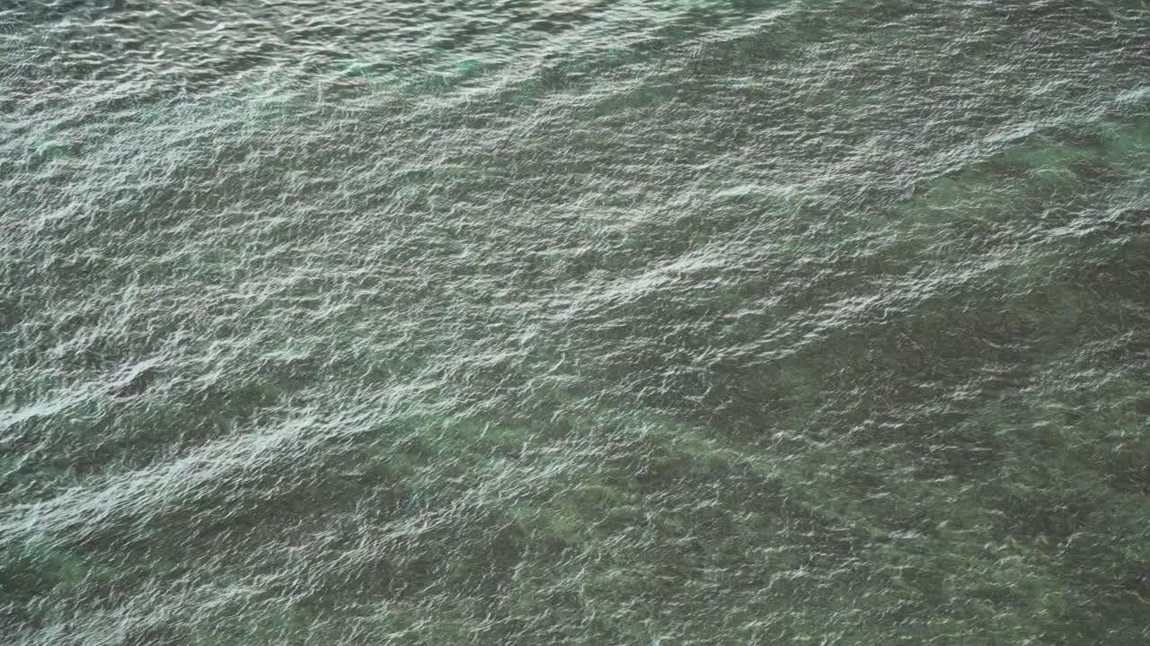 Sea waves reaching the shallow waters, bright reflecting water, high angle
