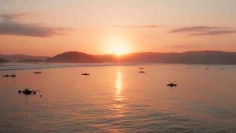 sunrise at the surf spots of gerupuk in lombok, with a view on the bay with the fishing boats and surfers