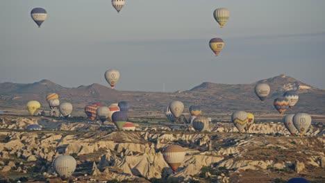 Popular-hot-air-ballooning-over-unique-Cappadocia-landscape-with-hoodoos,-Turkey