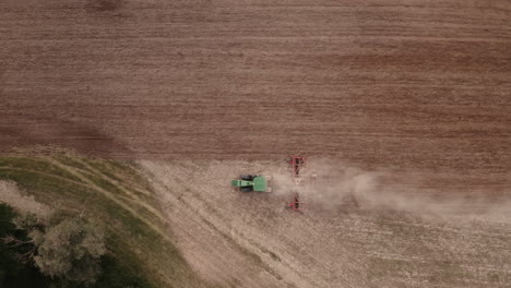 Aerial-top-view-of-tractor-cutting-furrows-in-farm-field-for-sowing-farm-tractor-with-rotary-harrow-plow-preparing-land-for-sowing