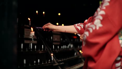 woman in kimono lighting candles at a temple