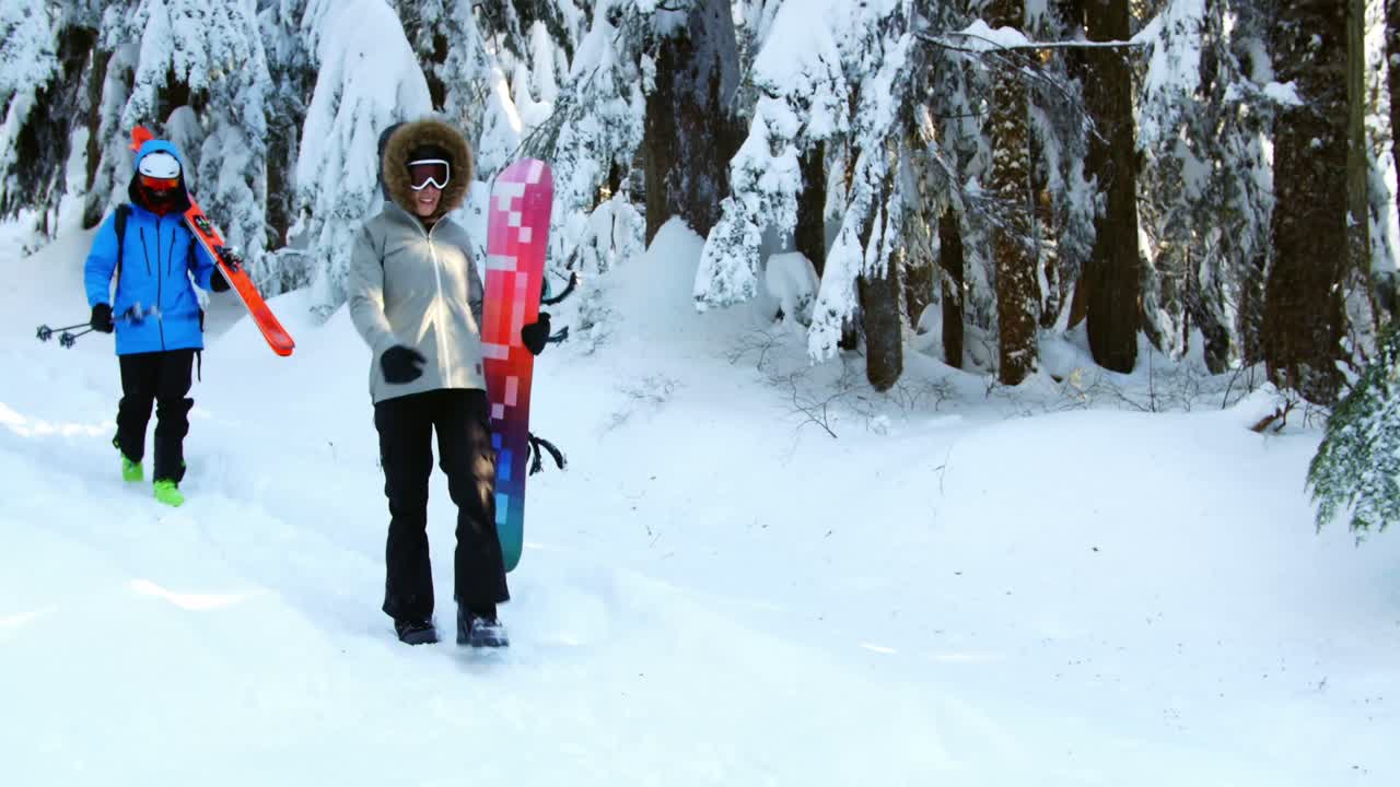pareja con snowboard caminando en la nieve 4k