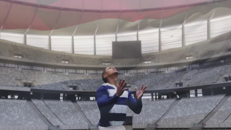 catching rugby ball, player in striped jersey in empty stadium