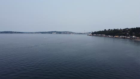 Low-angle-drone-shot-flying-over-the-Puget-Sound-with-a-ship-and-the-Space-Needle-in-the-background