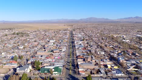 descending drone view of malargüe city layout with grid street pattern, arid terrain and cordillera de los andes mountain range on the horizon under clear skies in southern mendoza, argentina
