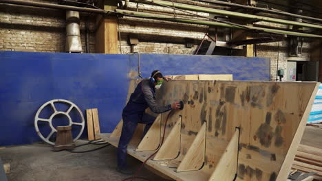 worker sanding wood panel in industrial setting