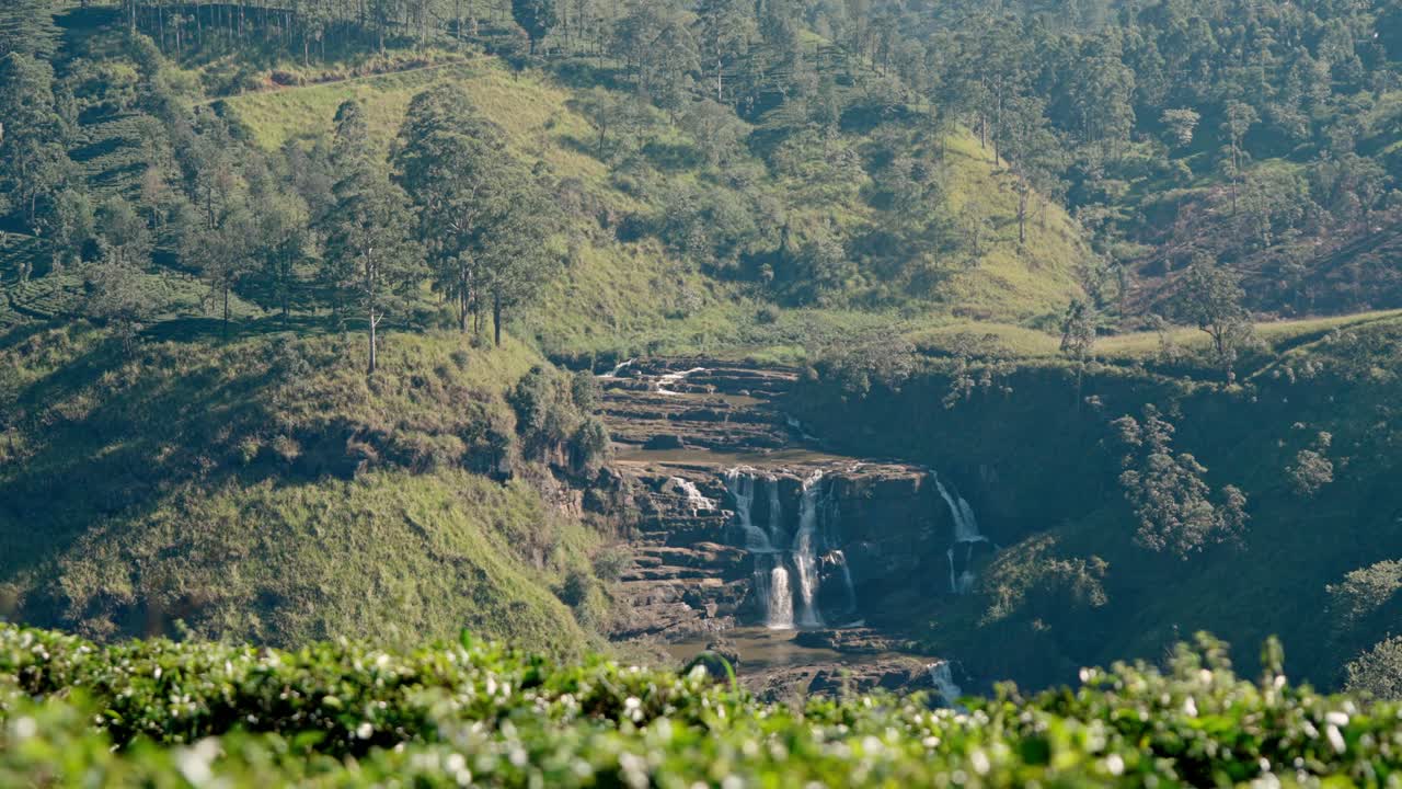 Scenic aerial view of Saint Clair’s Waterfall flowing through lush green tea plantations in the hills of Nuwara Eliya, Sri Lanka.